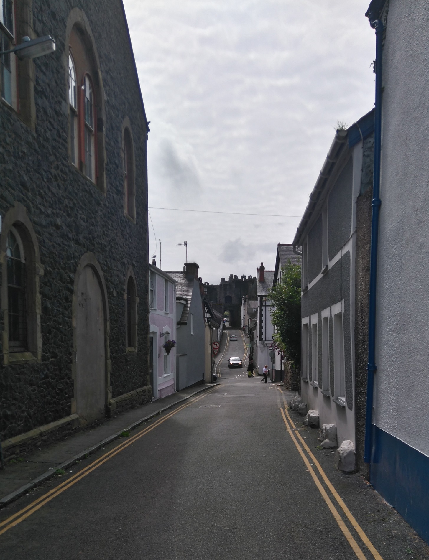 A narrow street in the historic Welsh town of Conwy. The ancient town walls are visible in the distance.