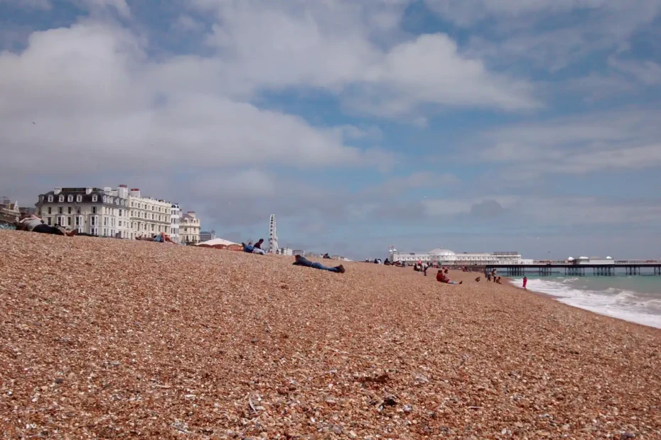 Brighton beach on a sunny day with the pier and eye visible in the background.